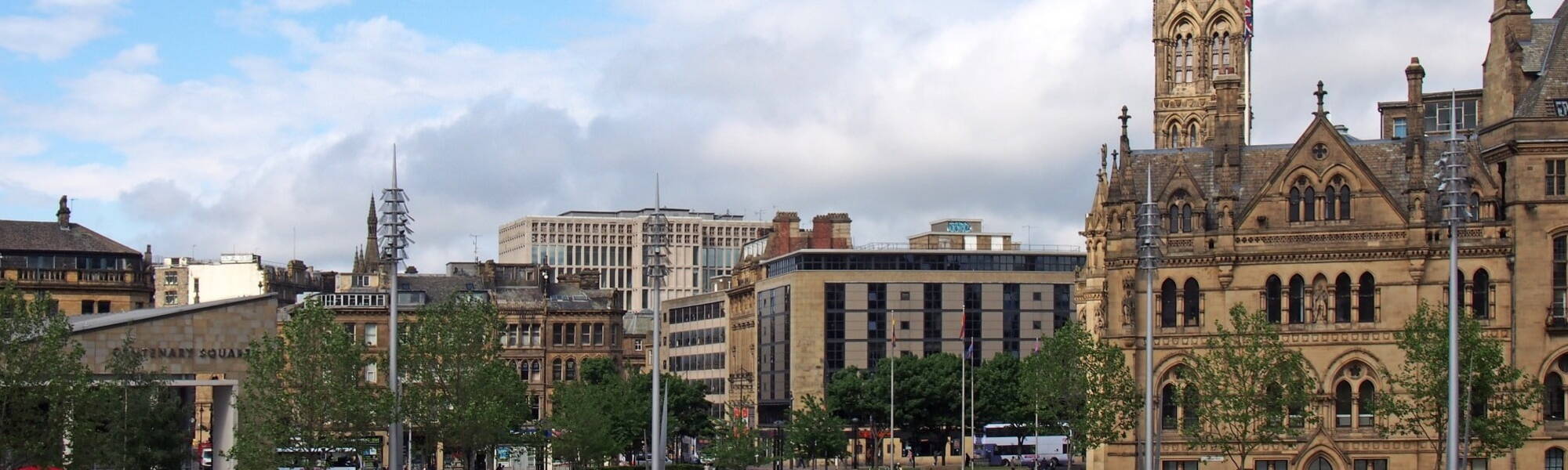 a cityscape view of centenary square and town centre in bradford west yorkshire with people sitting and walking past the city hall and main streets