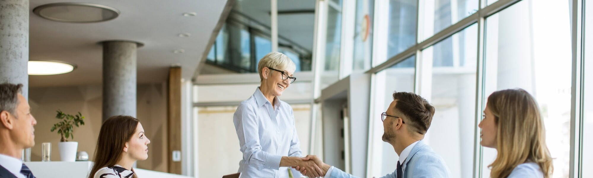 female business leader shaking hands with board members at a board meeting