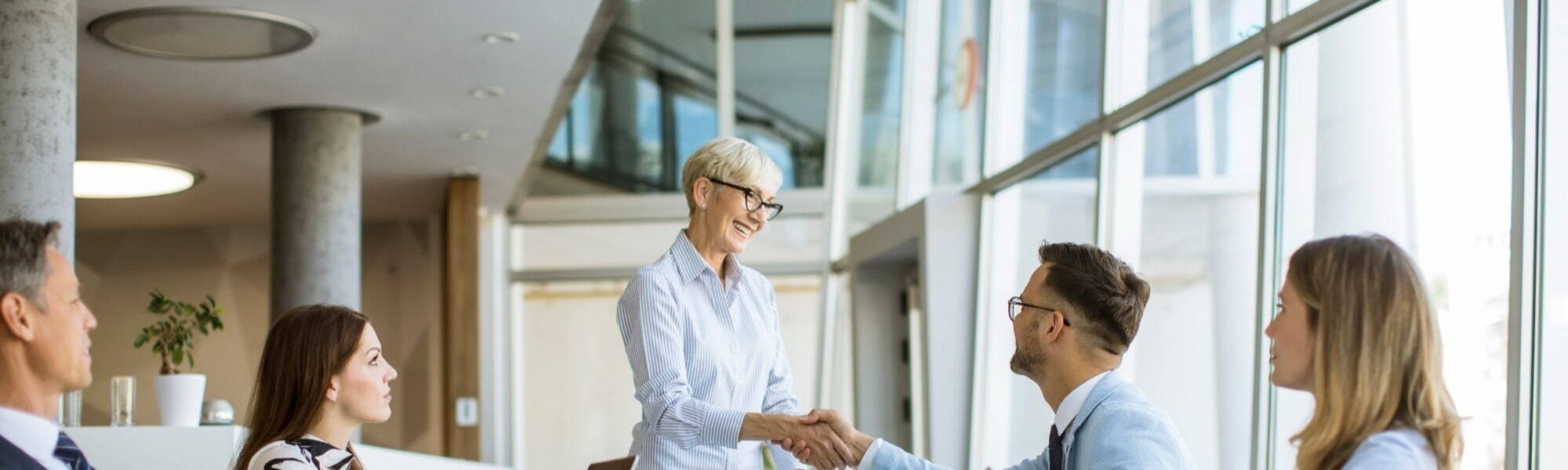 professional women skakiing hands in a corporate meeting with her team members