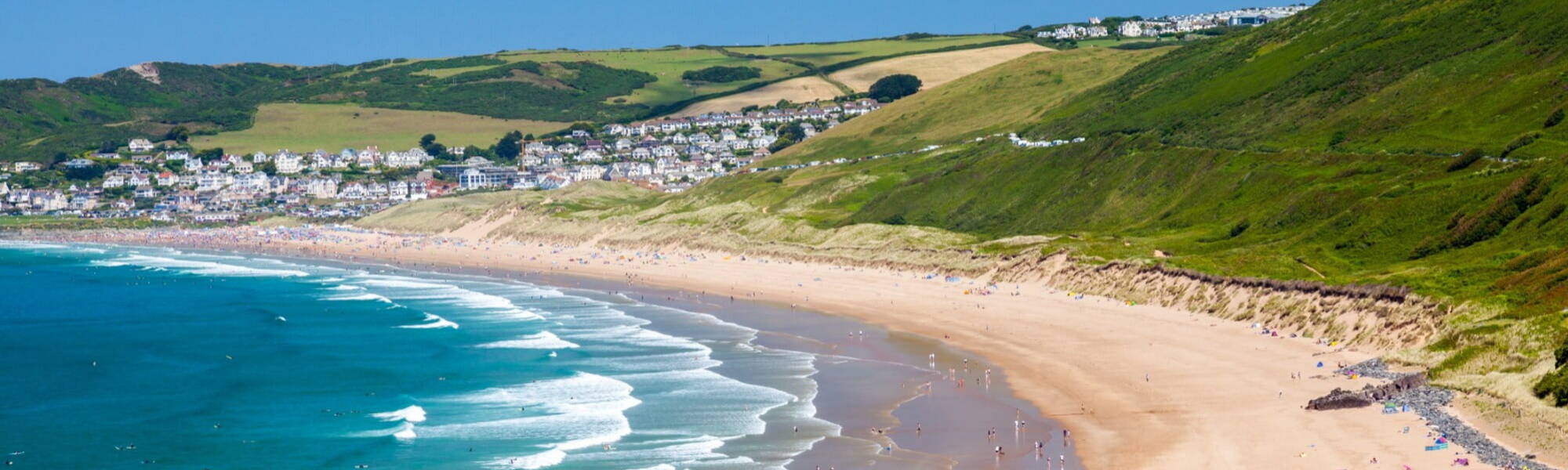 Devon coatline, sunny beach and green cliffs of Putsborough Sands