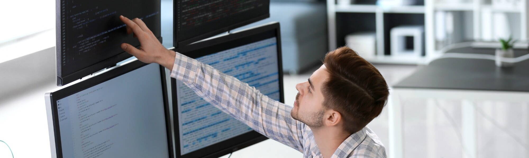 Software engineer typing source code on computer keyboard while colleagues sit down at desk for group project. App developer working in it startup company doing online cloud computing.