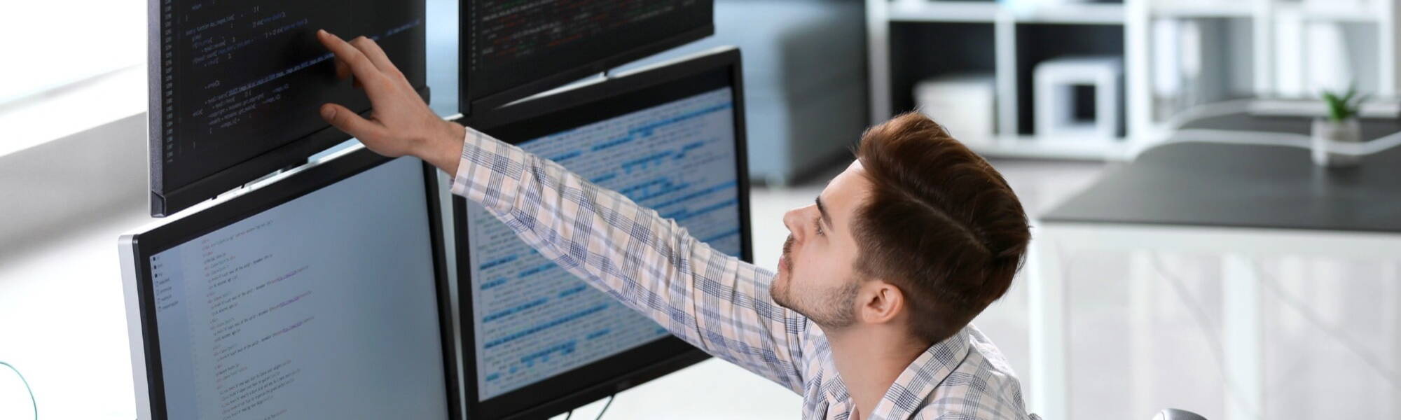 Software engineer typing source code on computer keyboard while colleagues sit down at desk for group project. App developer working in it startup company doing online cloud computing.