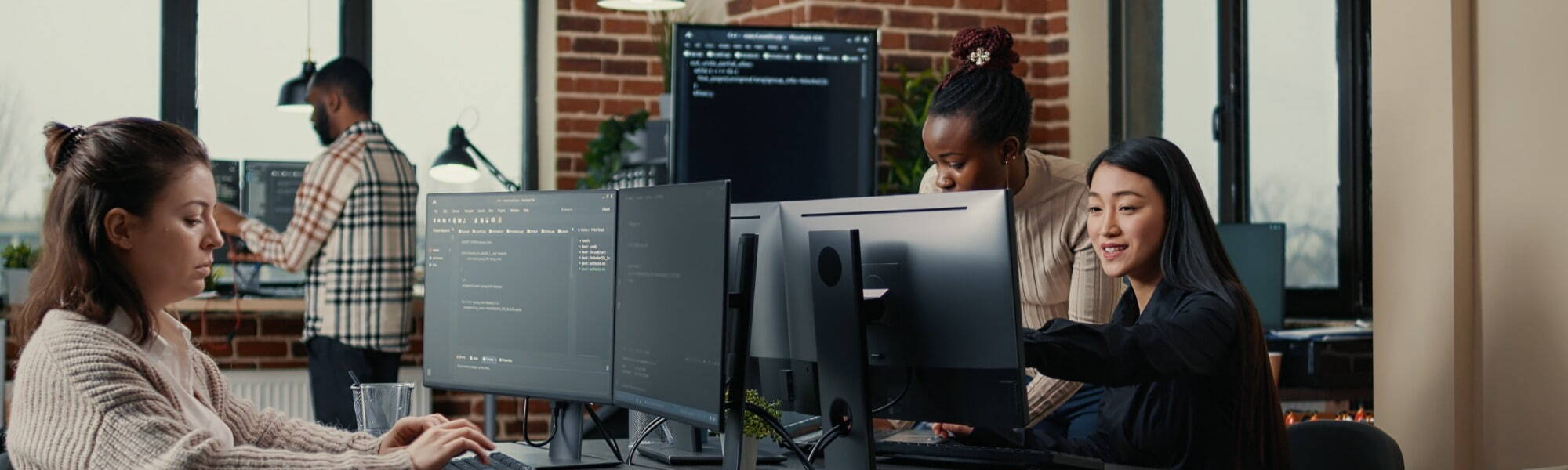 Software engineer typing source code on computer keyboard while colleagues sit down at desk for group project. App developer working in it startup company doing online cloud computing.